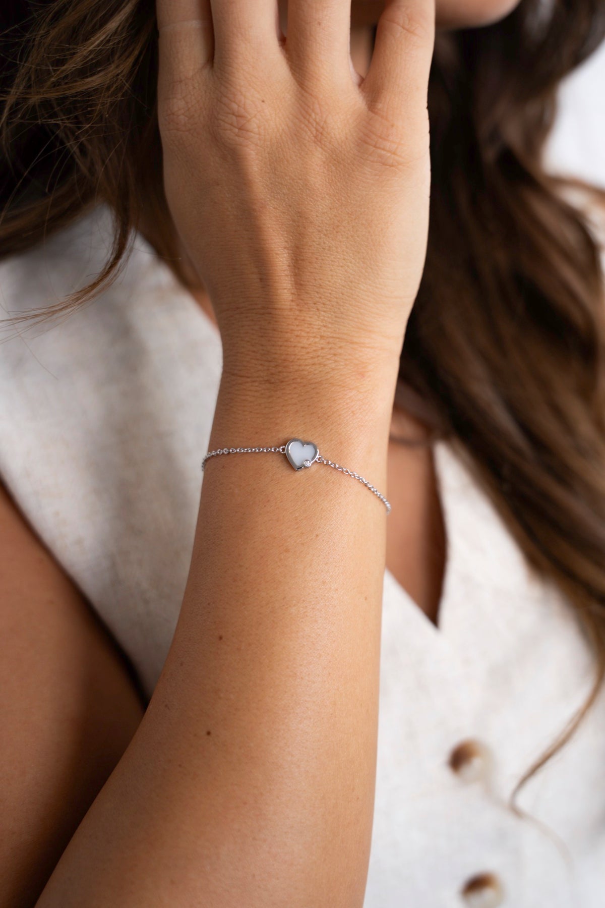 Close-up van de zilveren Esmée moedermelkarmband met hartje aan een fijne schakelketting.