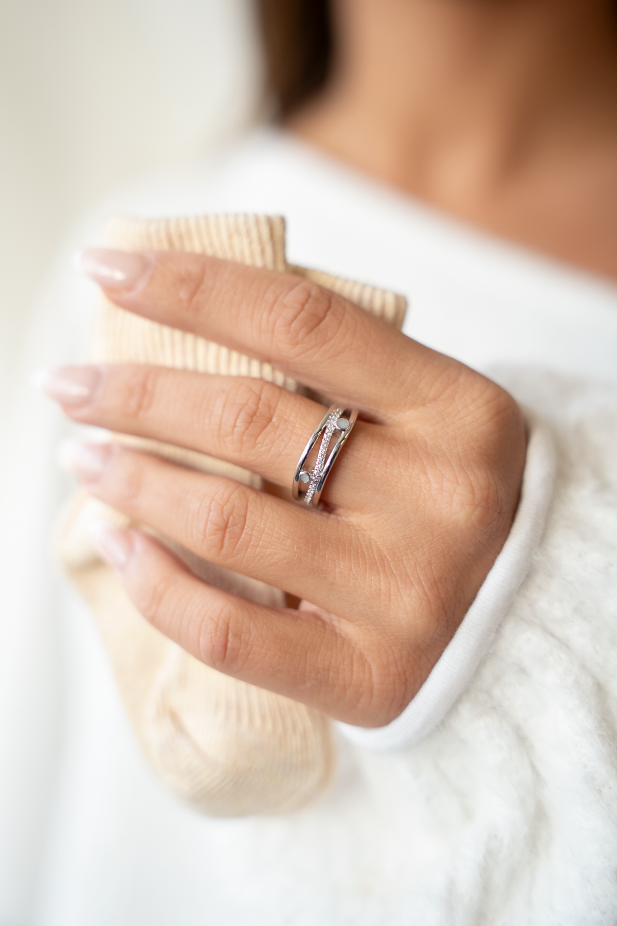 Massief witgouden ring met een heldere zirkonia en een vlak van moedermelk, gedragen door een persoon.