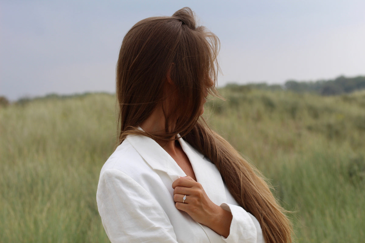 Moedermelk-ring van 925 zilver, eenvoudig ontwerp met een glanzende afwerking, gedragen door een vrouw met lang haar in een groene omgeving.