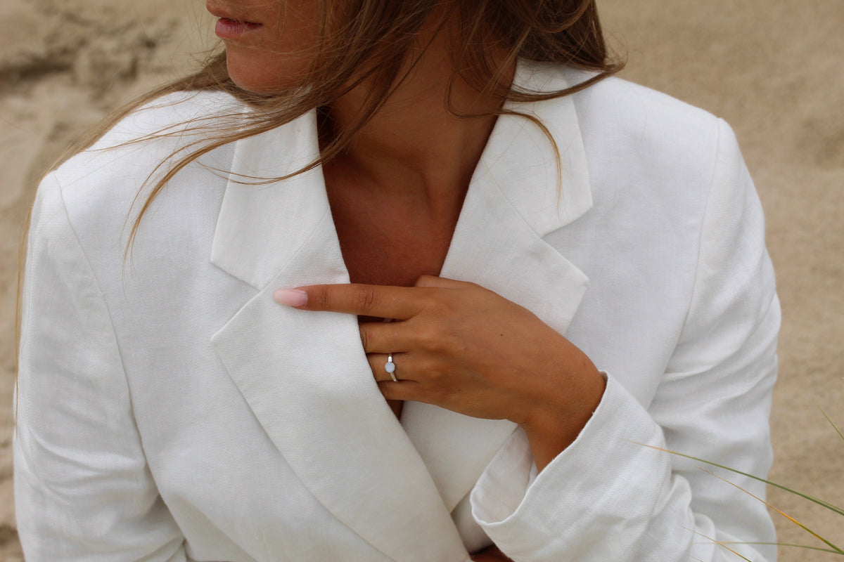 Moedermelk-ring van 925 zilver met een heldere steen, gedragen door een vrouw in een witte blazer.