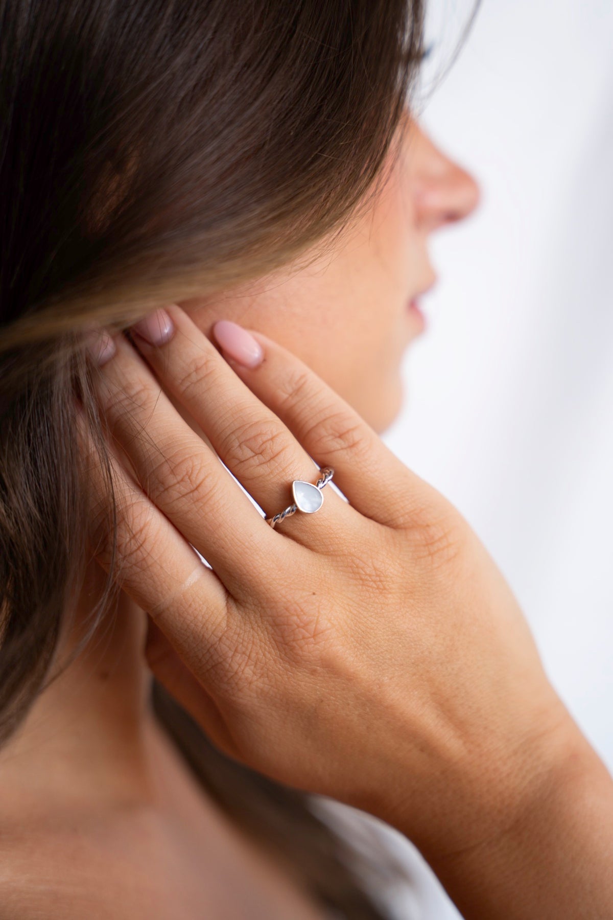 Hand bij het oor met de Turning Droplet moedermelkring van 925 zilver.