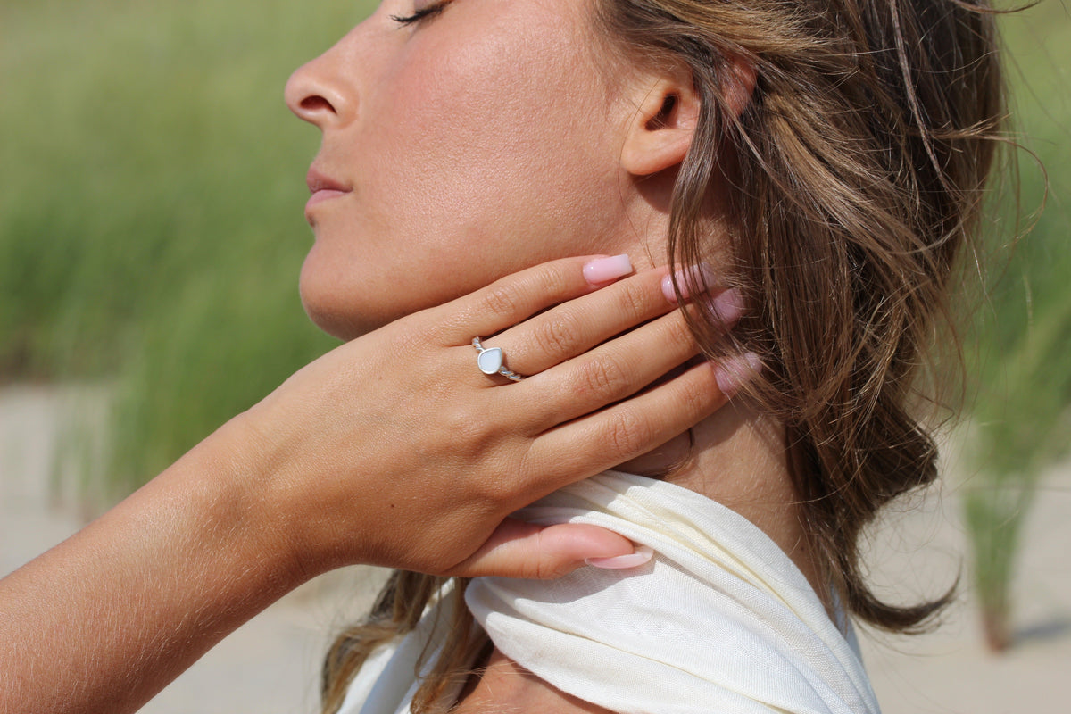 Moedermelk-ring in 925 zilver met een druppelvormige harssteen, gedragen door een vrouw met een natuurlijke uitstraling.